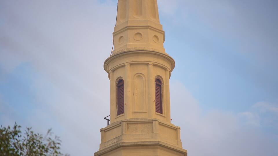 A church steeple with a clock and a weather vane.