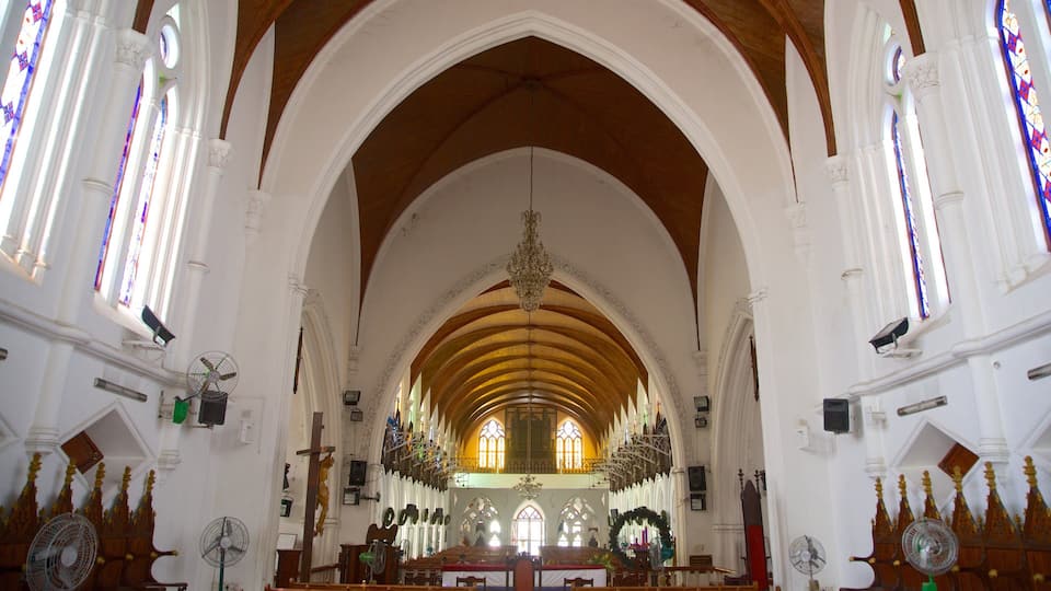 Interior de iglesia con techos abovedados, vidrieras de colores y un altar central.