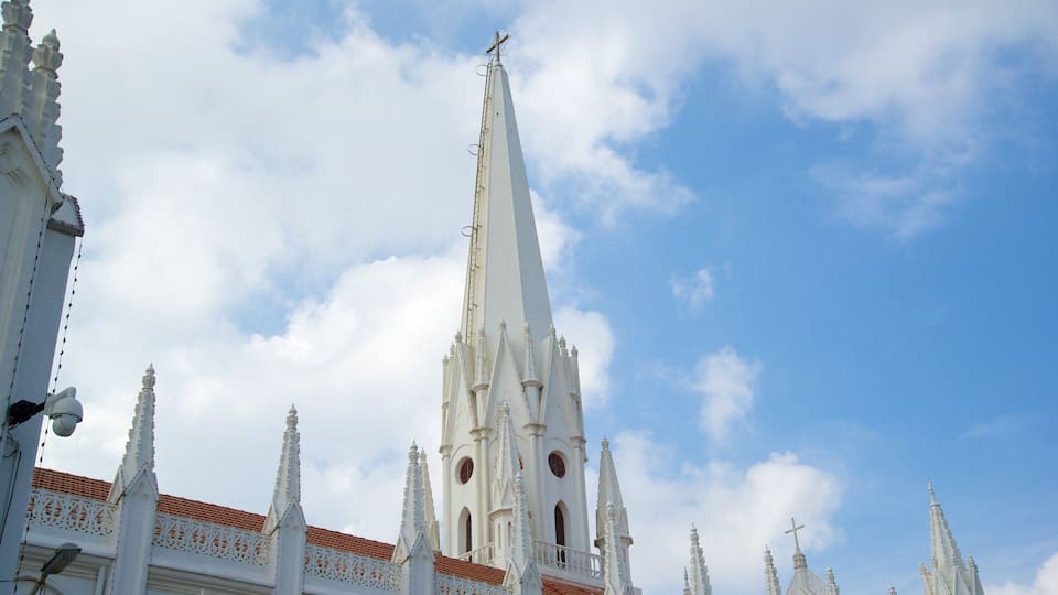 Una iglesia blanca con una aguja alta y varias torres puntiagudas bajo un cielo parcialmente nublado.