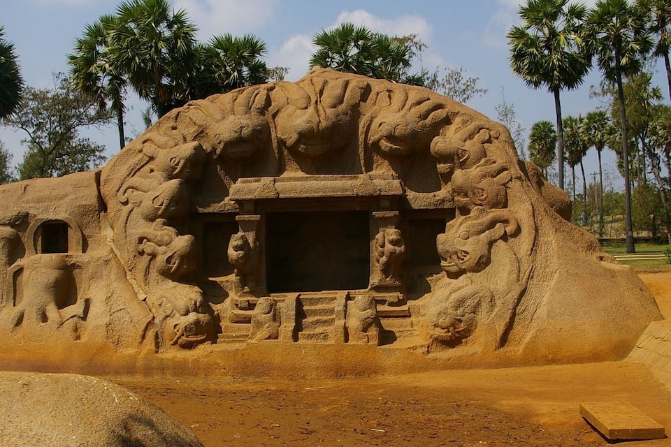 A large, ancient stone structure with intricate carvings, including a central doorway and surrounding figures.
