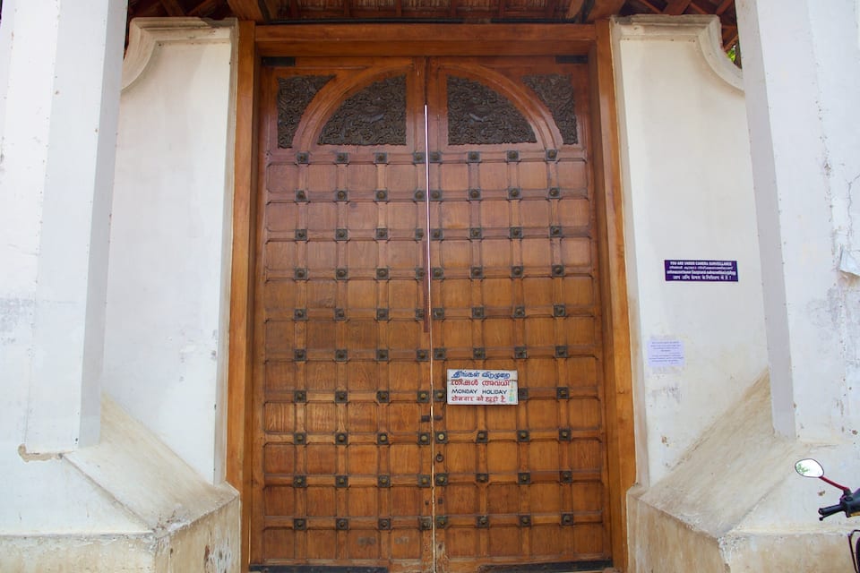 A large wooden door with a sign indicating it is closed on Monday holidays.