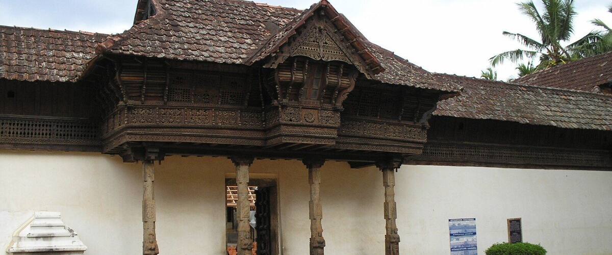 A traditional wooden building with a tiled roof and intricate carvings.