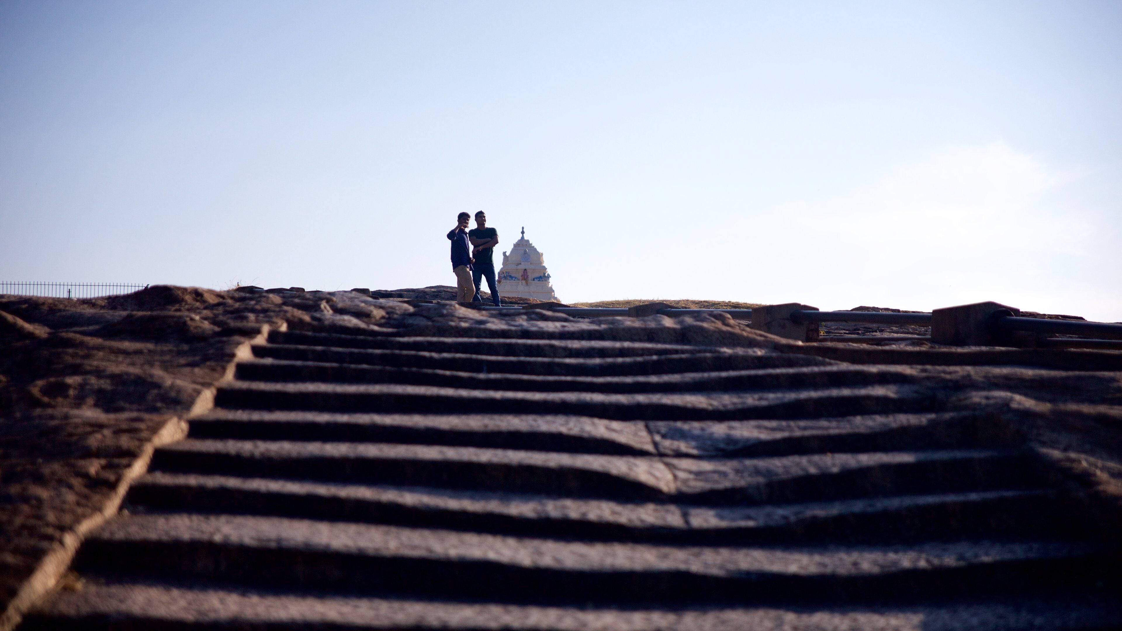 Uma escadaria de pedra que leva a um templo branco, com duas pessoas no topo.