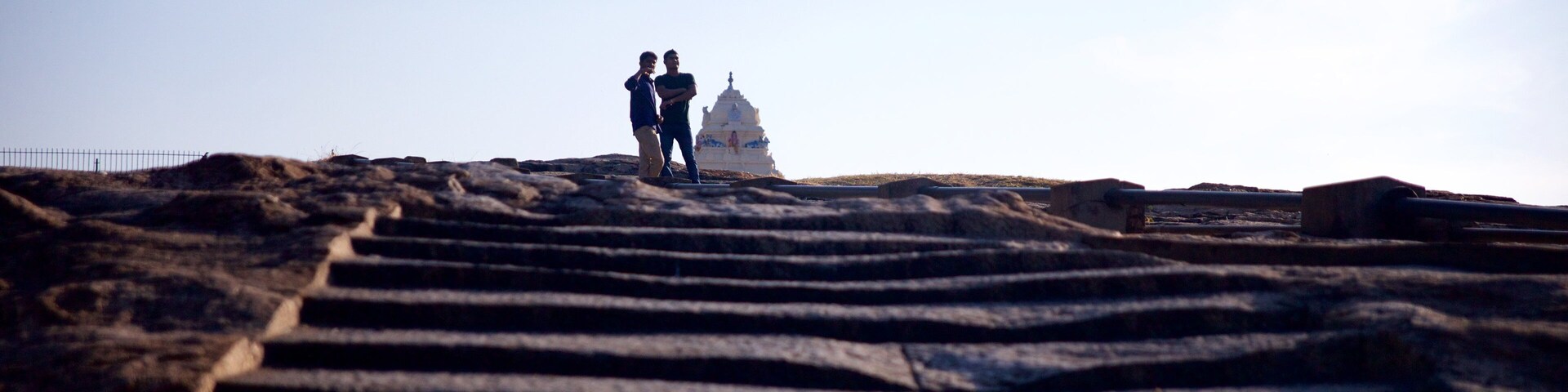 Uma escadaria de pedra que leva a um templo branco, com duas pessoas no topo.