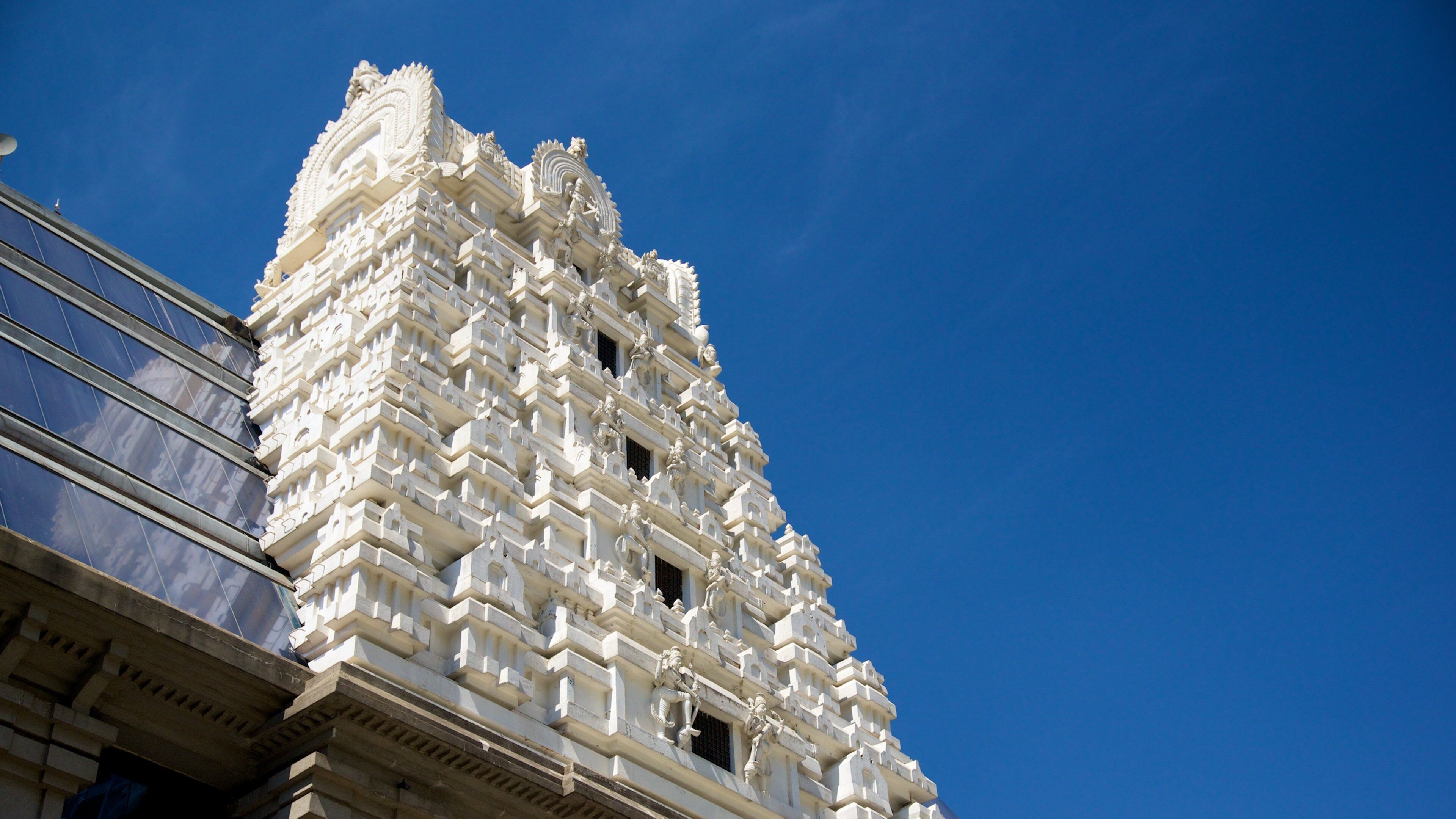 A white temple with intricate carvings against a clear blue sky.