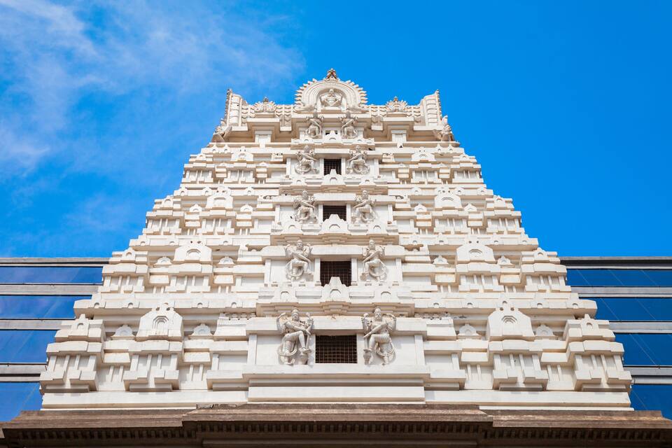 Un templo blanco con intrincados grabados y estatuas, con un cielo azul de fondo.