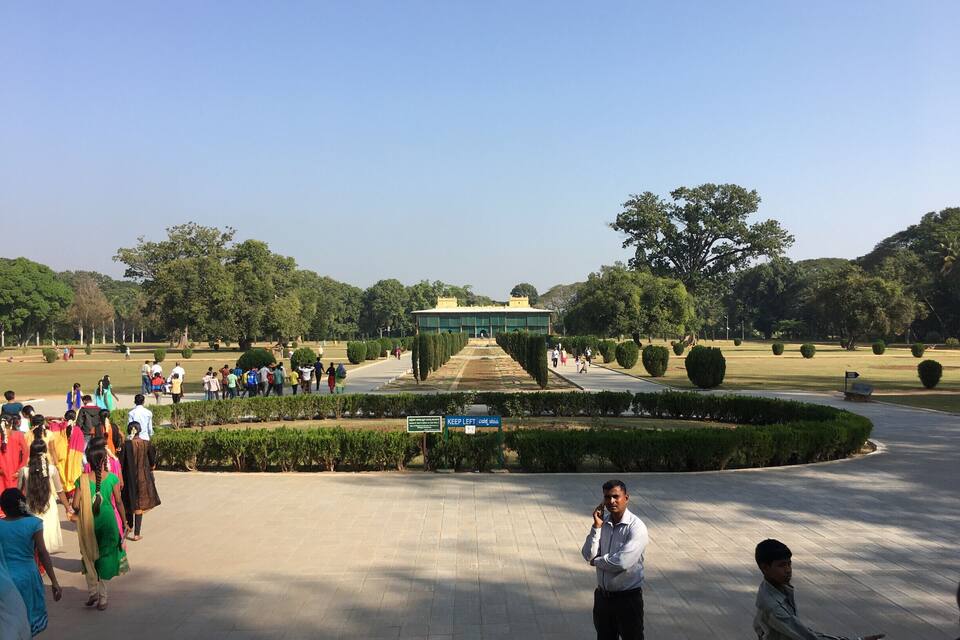 A park with a central building, pathways, and people walking.