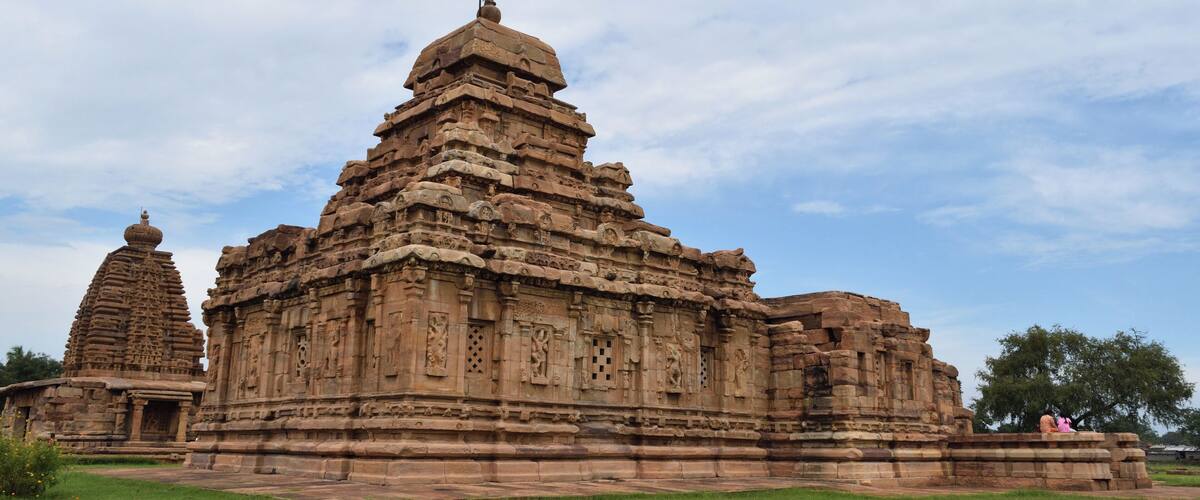 A large, intricately carved temple with multiple tiers and a smaller structure nearby.