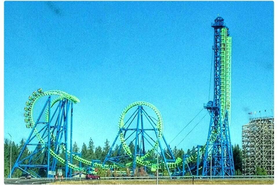 A roller coaster with two large green wheels and a tall blue tower.