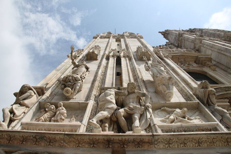 A detailed stone facade with classical sculptures and architectural elements.