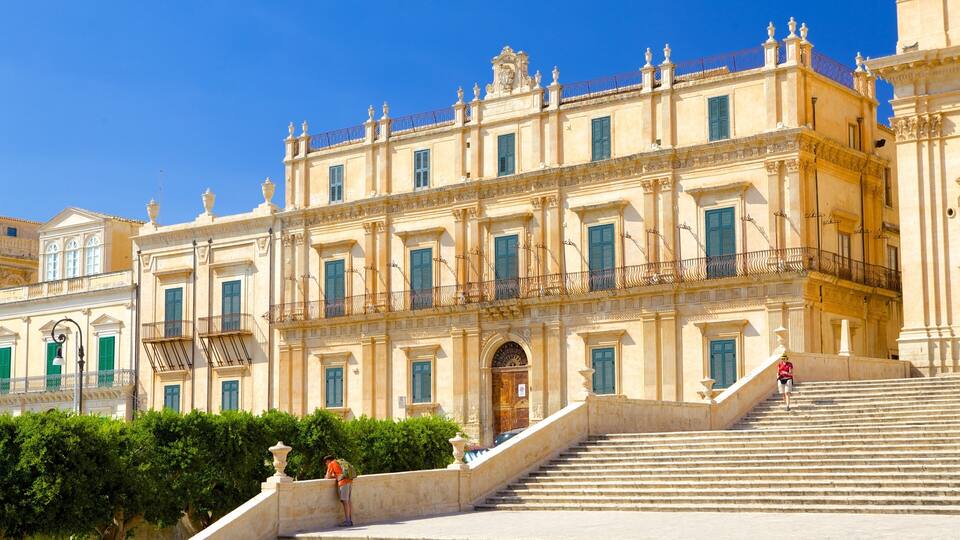 A grand historical building with ornate balconies and a staircase leading to the entrance.