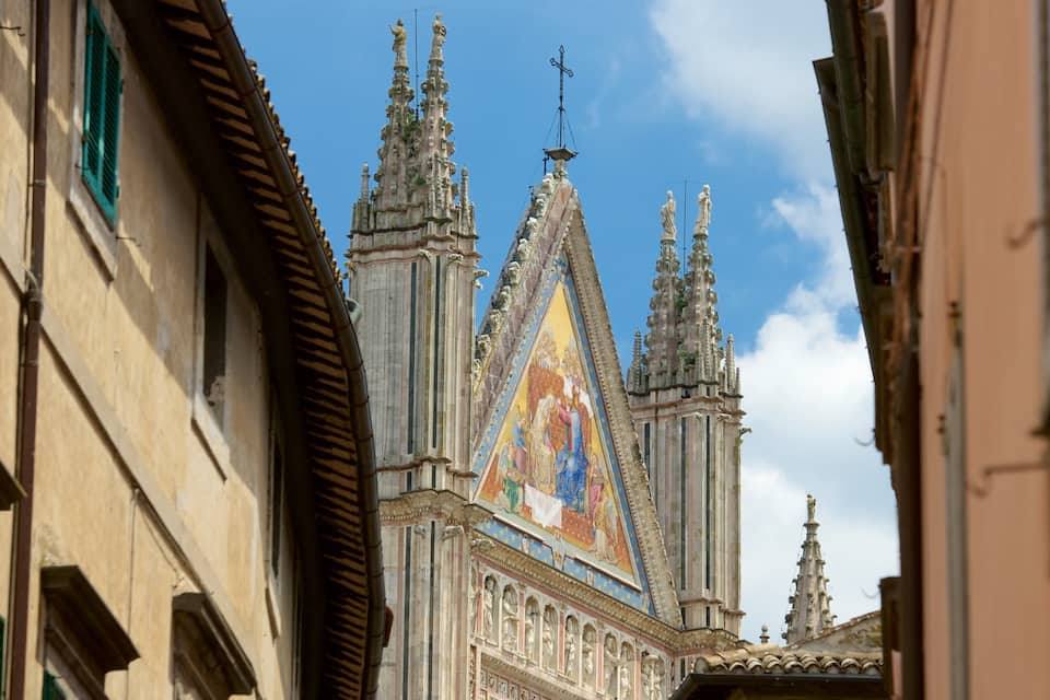Una catedral con una aguja puntiaguda y un mosaico colorido en la fachada.
