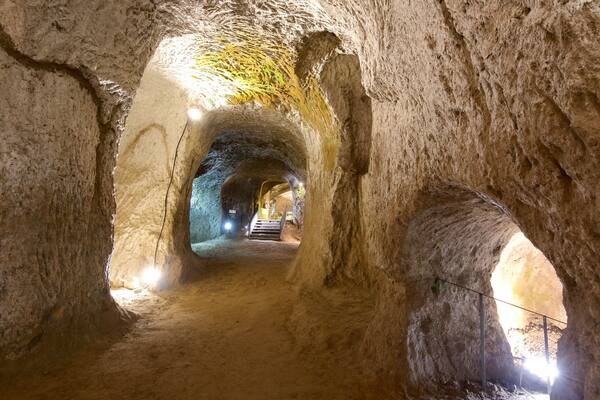 Une grotte avec un étroit passage et un escalier menant à un niveau supérieur.
