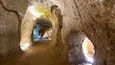 A cave with a narrow passageway and a staircase leading to a higher level.