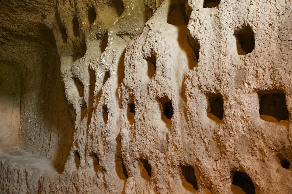 Una pared rocosa con varios agujeros y una textura rugosa.