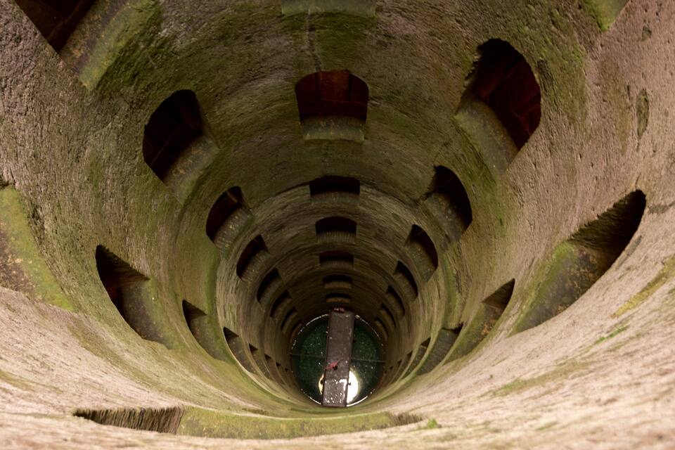 Una escalera espiral de piedra con una persona en la parte inferior.