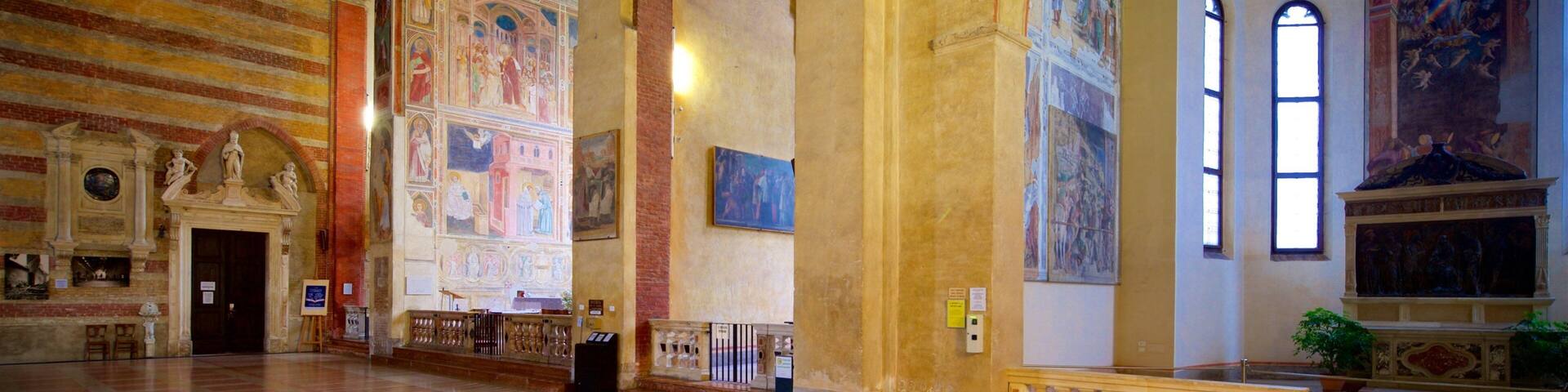 A grand hall with high vaulted ceilings, intricate frescoes, and a large circular window.
