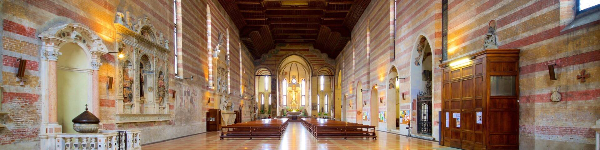 A church interior with a long nave, arched ceiling, and rows of pews.