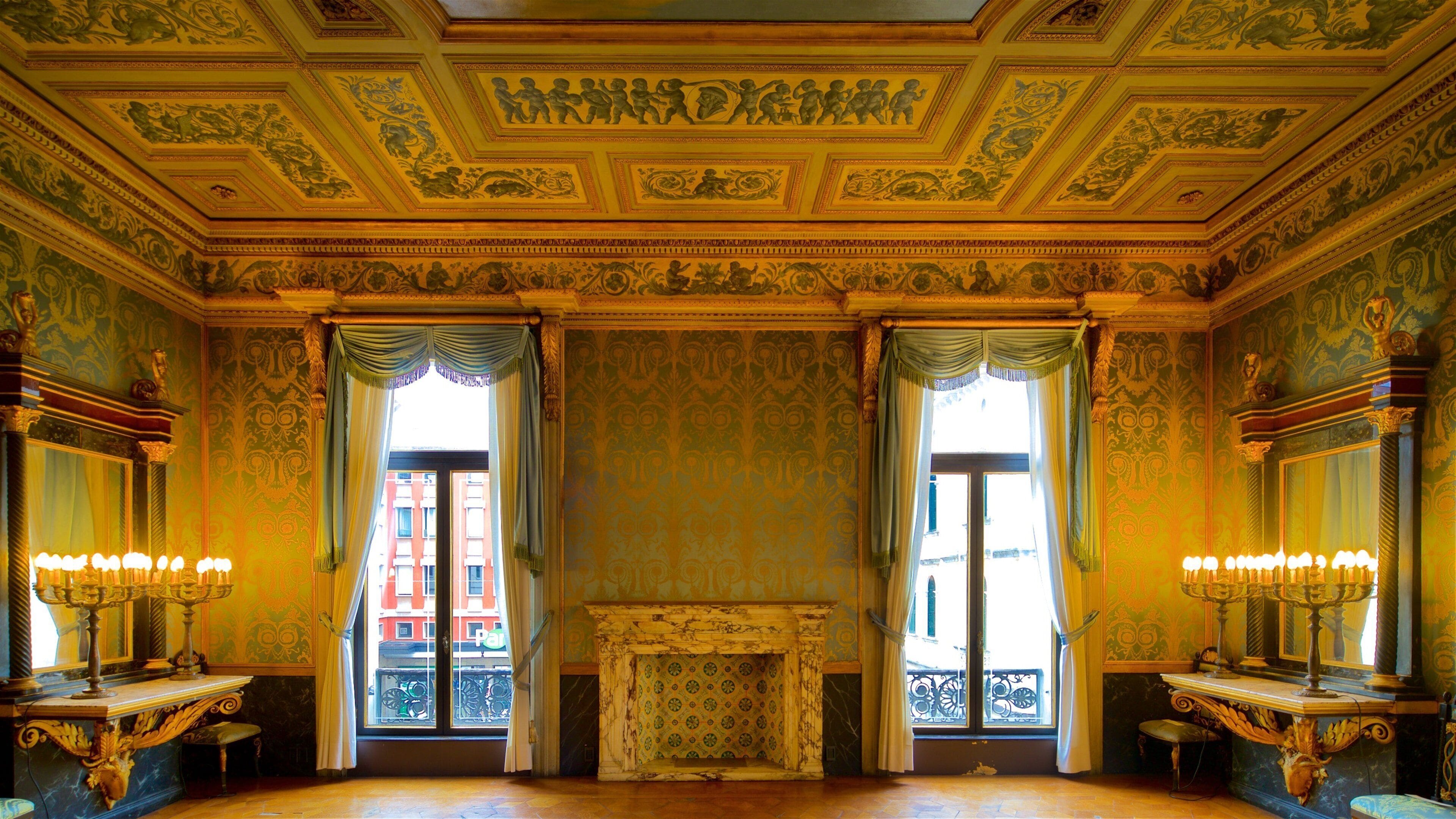 An ornate room with a fireplace, decorative moldings, and two windows with curtains.
