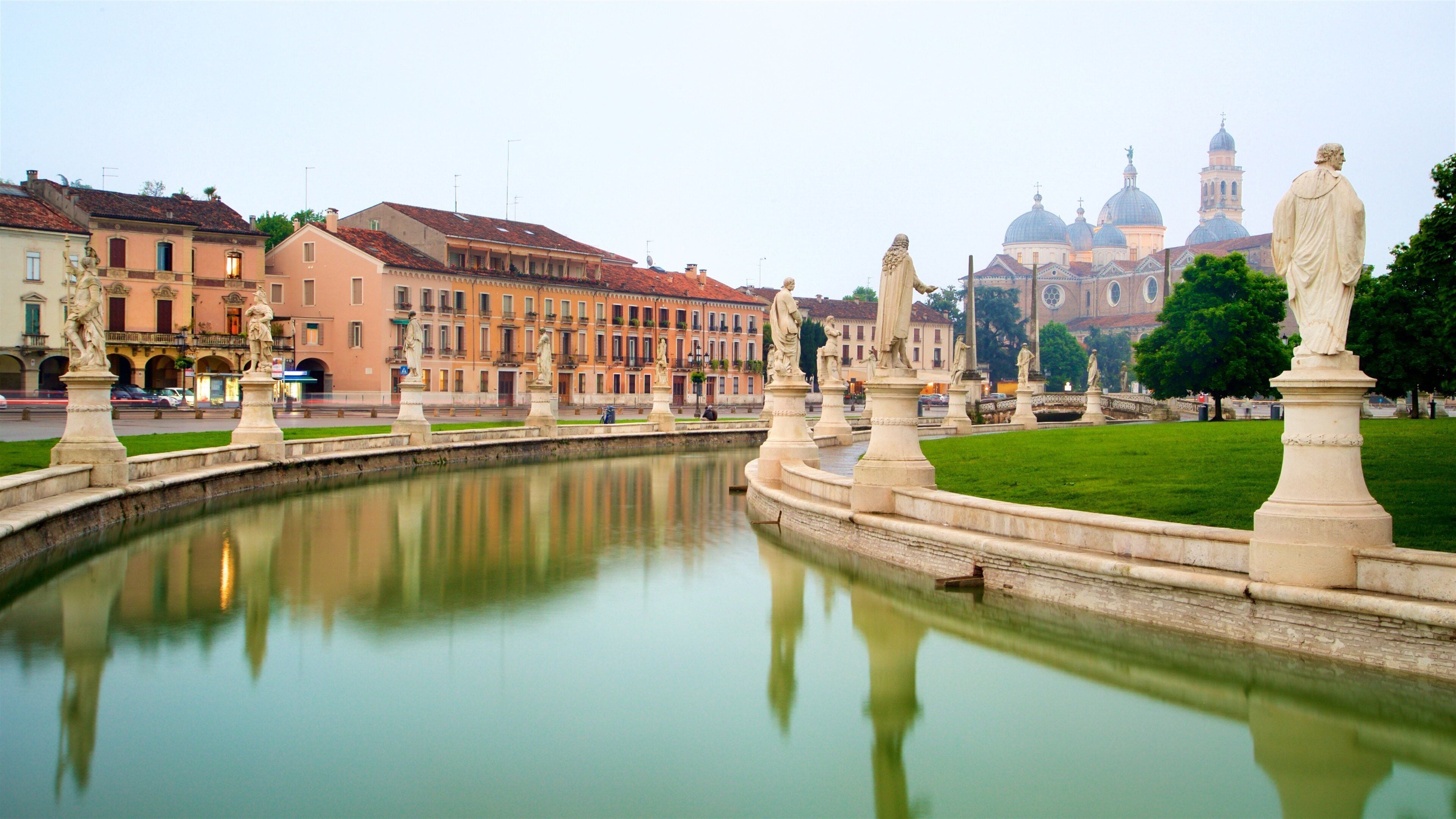 A canal with statues, a church with domes, and historic buildings.
