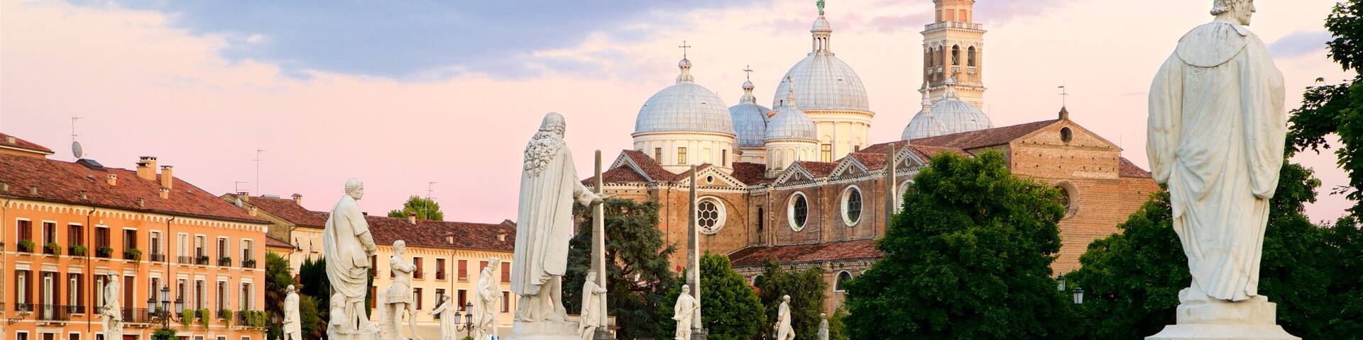 Une fontaine historique ornée de statues, une rivière et une église avec des coupoles en arrière-plan.