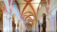L’intérieur d’une cathédrale, avec de hauts plafonds en voûte, des fenêtres en arc de cercle et un crucifix.