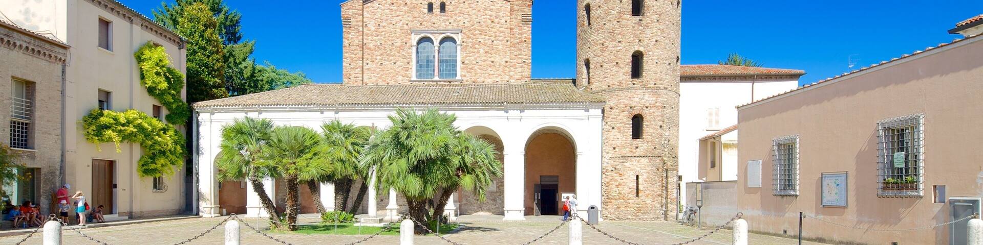 A historic church with a tall bell tower, surrounded by cobblestone streets and palm trees.