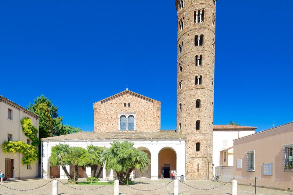 Eine historische Kirche mit einem hohen Glockenturm, umgeben von Kopfsteinpflasterstraßen und Palmen.