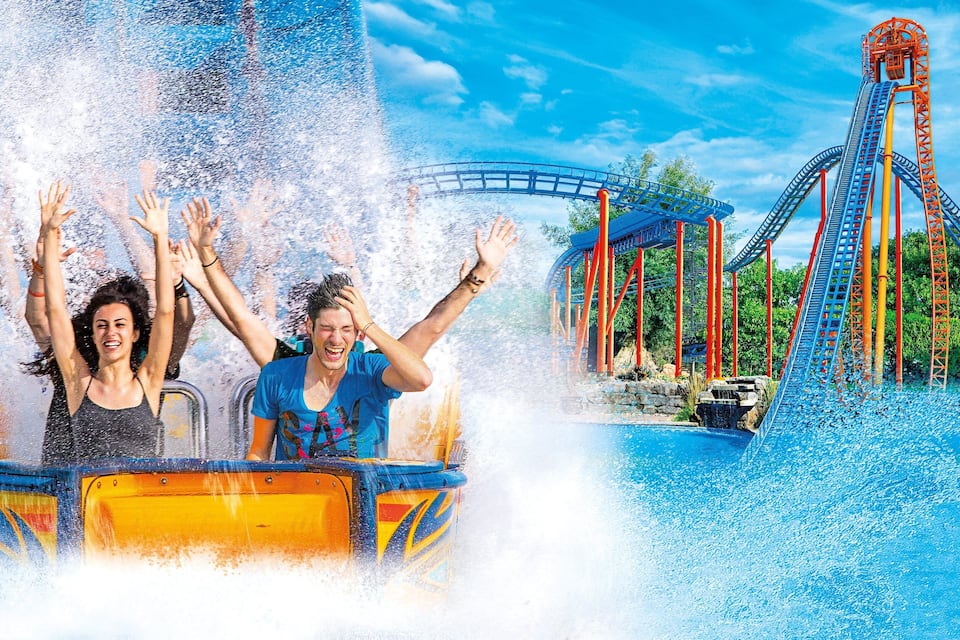 A water ride with a roller coaster in the background.