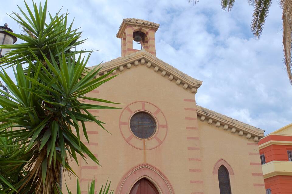 Uma igreja com uma torre de sino, uma janela redonda e uma porta vermelha.