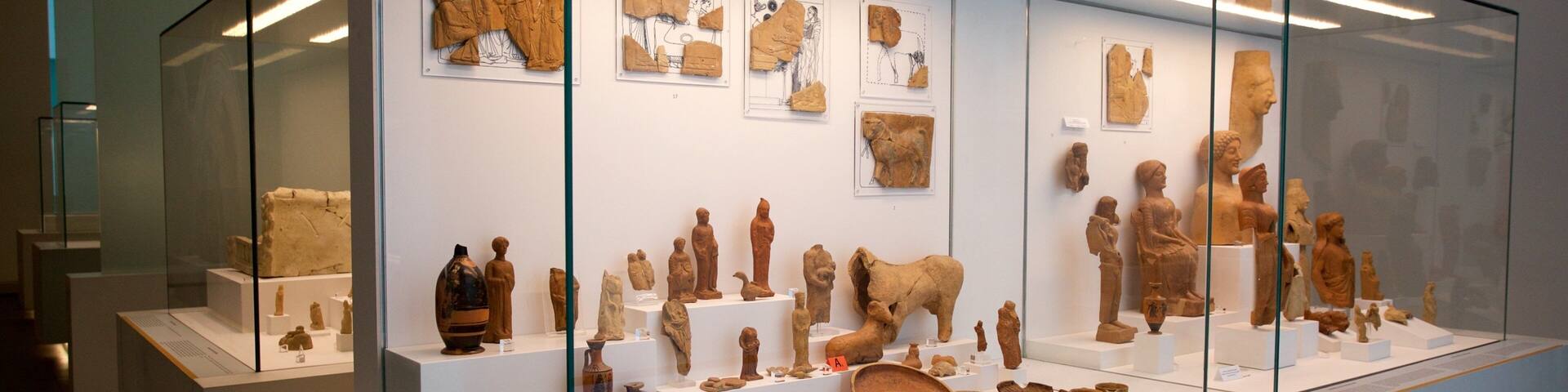 A museum exhibit with ancient pottery, sculptures, and wall art.