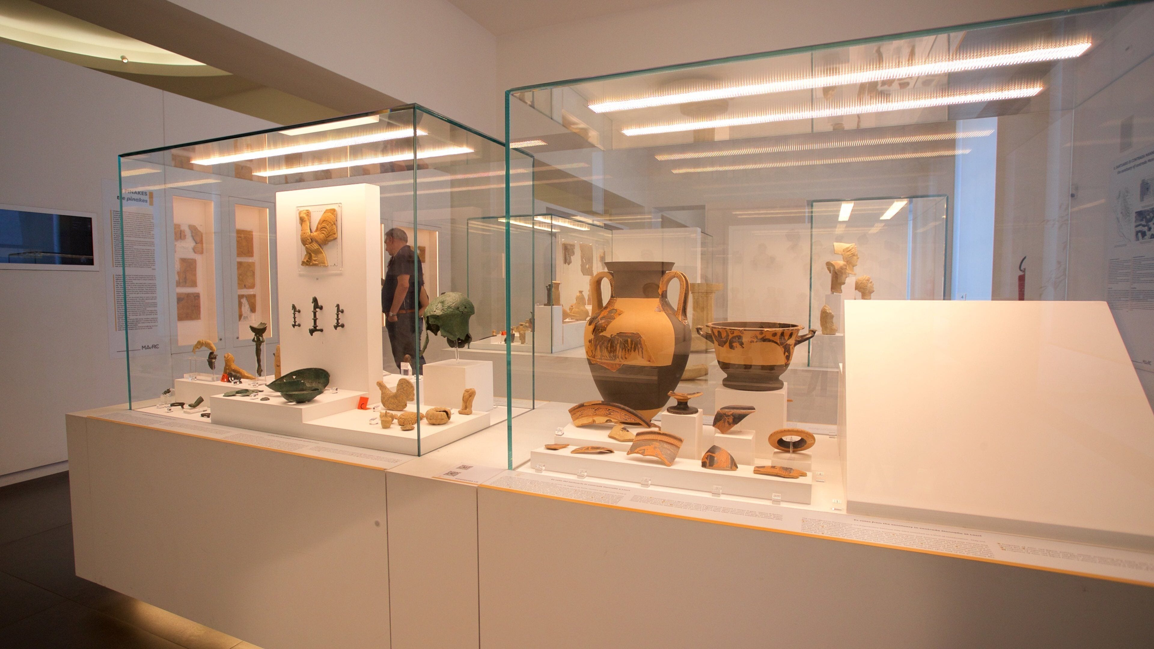 An indoor museum exhibit with glass display cases containing ancient pottery and artifacts.