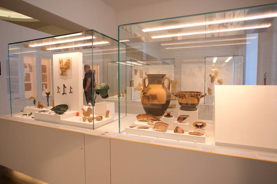 An indoor museum exhibit with glass display cases containing ancient pottery and artifacts.