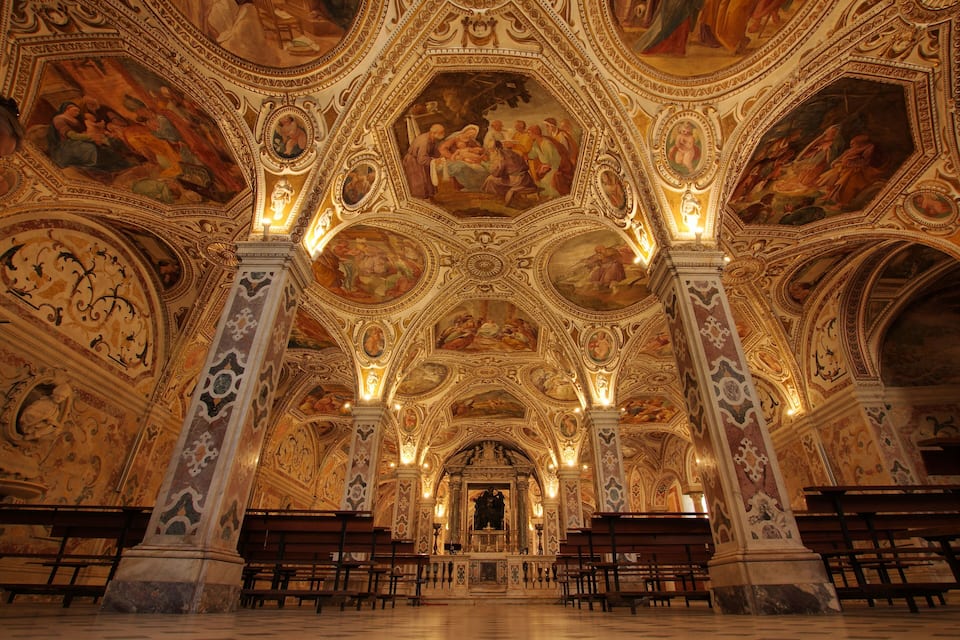 An ornate church interior with detailed frescoes and gold accents.