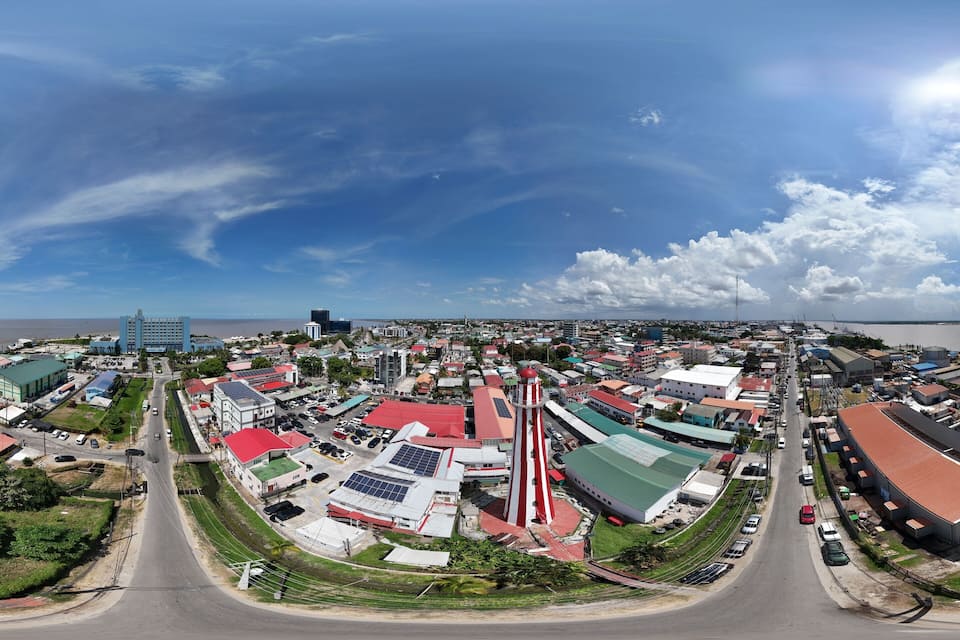 An aerial view of a coastal town with a prominent lighthouse, a marina, and various buildings along the waterfront.