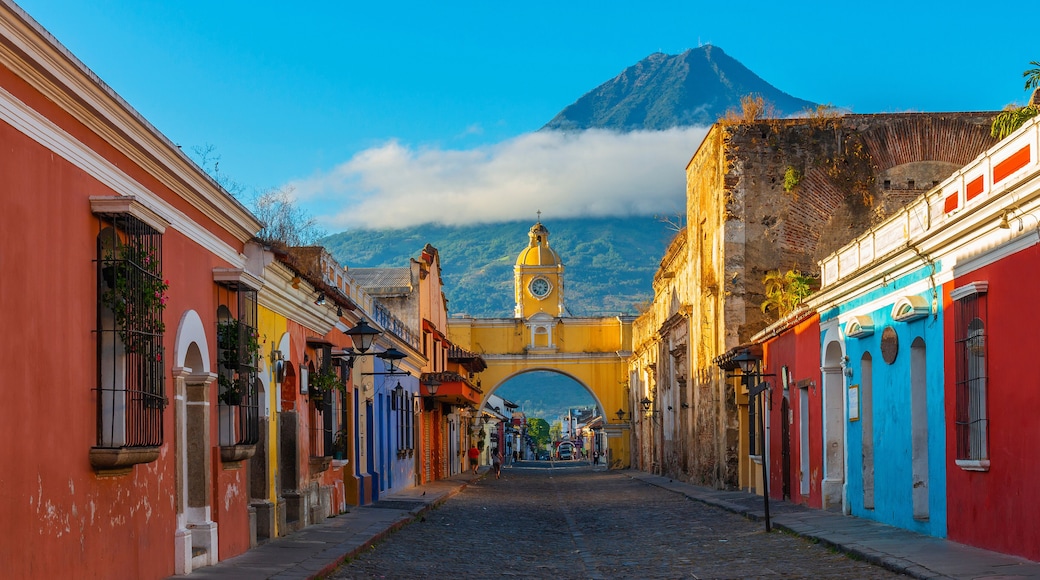 Cityscape of the main street and yellow Santa Catalina arch in the historic city center of Antigua at sunrise with the Agua volcano, Guatemala.