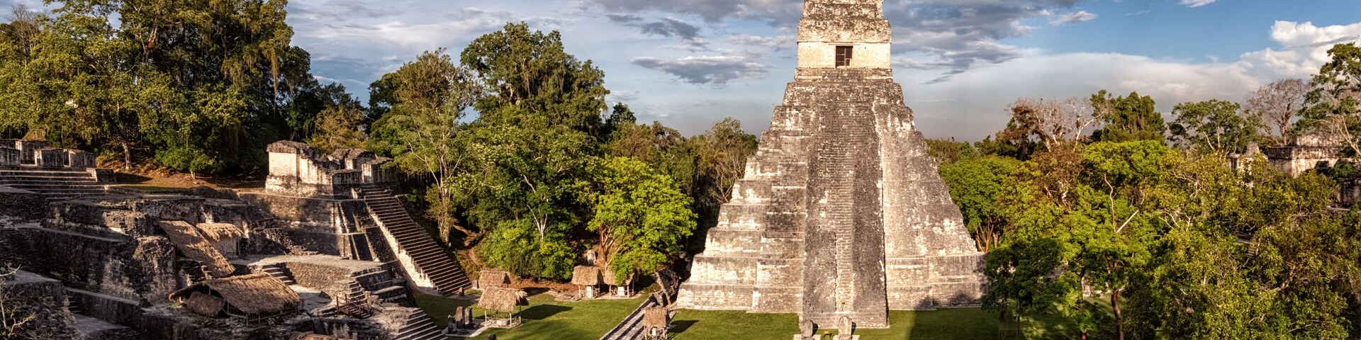 An ancient pyramid surrounded by lush greenery and smaller structures.
