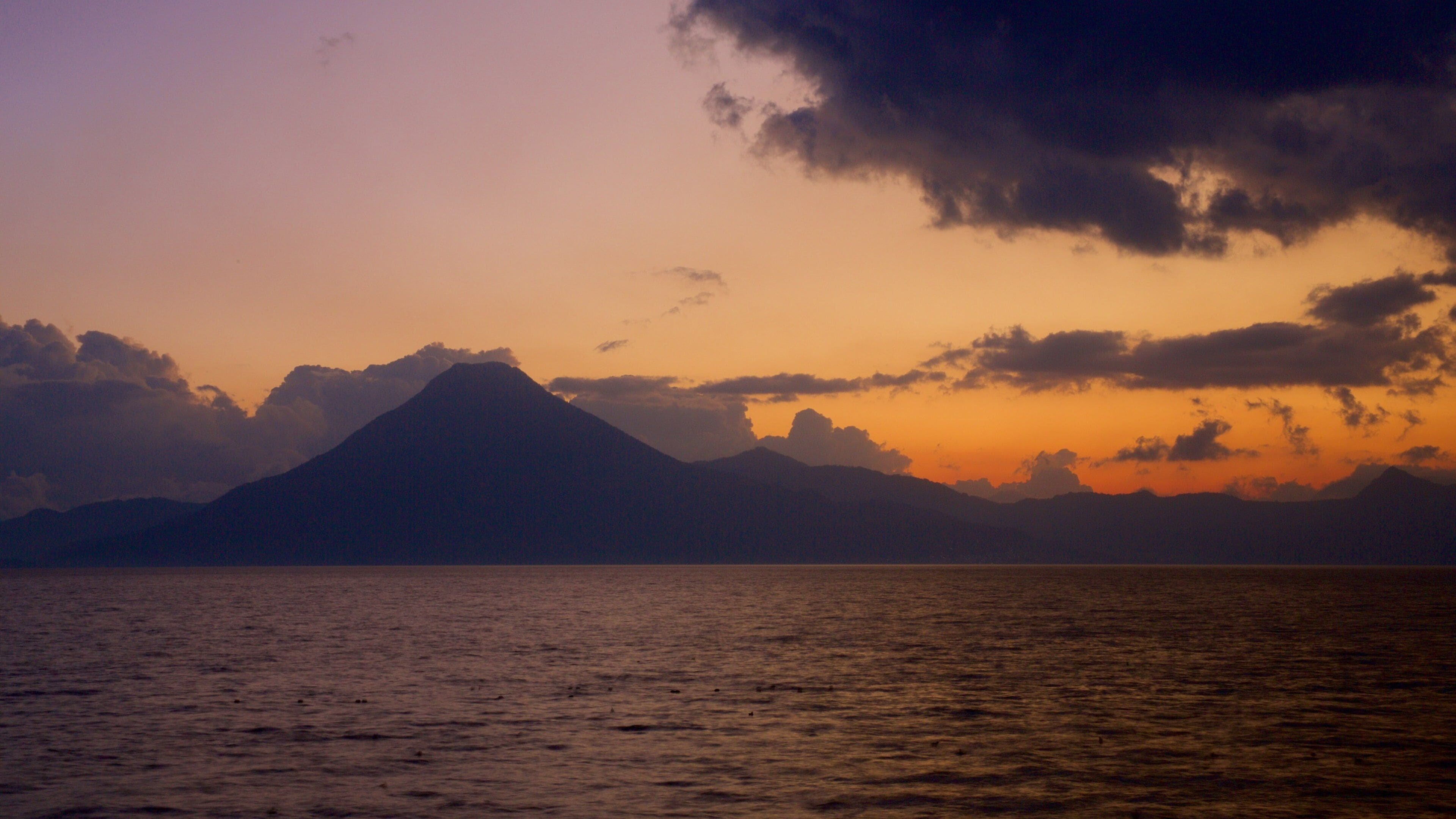 Atitlan Volcano which includes general coastal views, mountains and a sunset