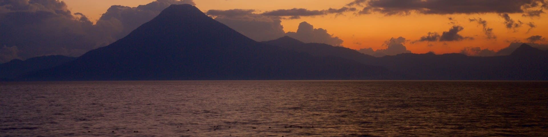 Atitlan Volcano which includes general coastal views, mountains and a sunset