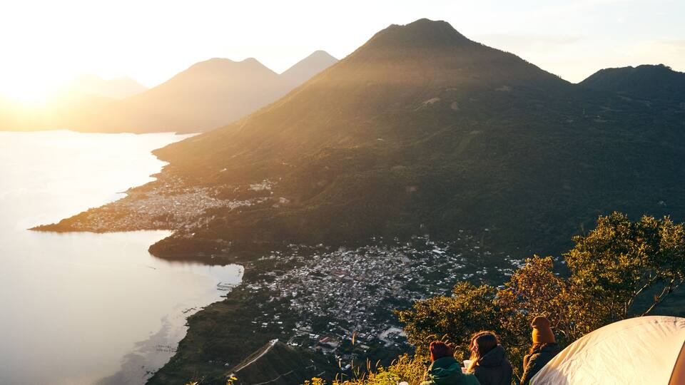 A mountainous landscape with a body of water and a town below.