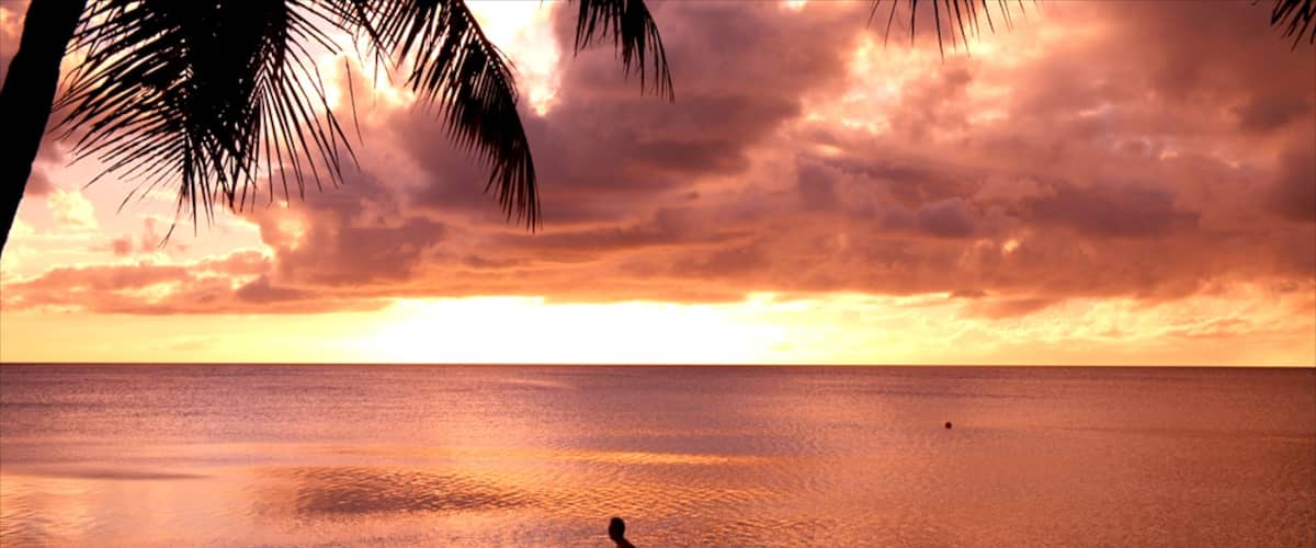 Tumon Beach ofreciendo una playa y un atardecer y también un hombre