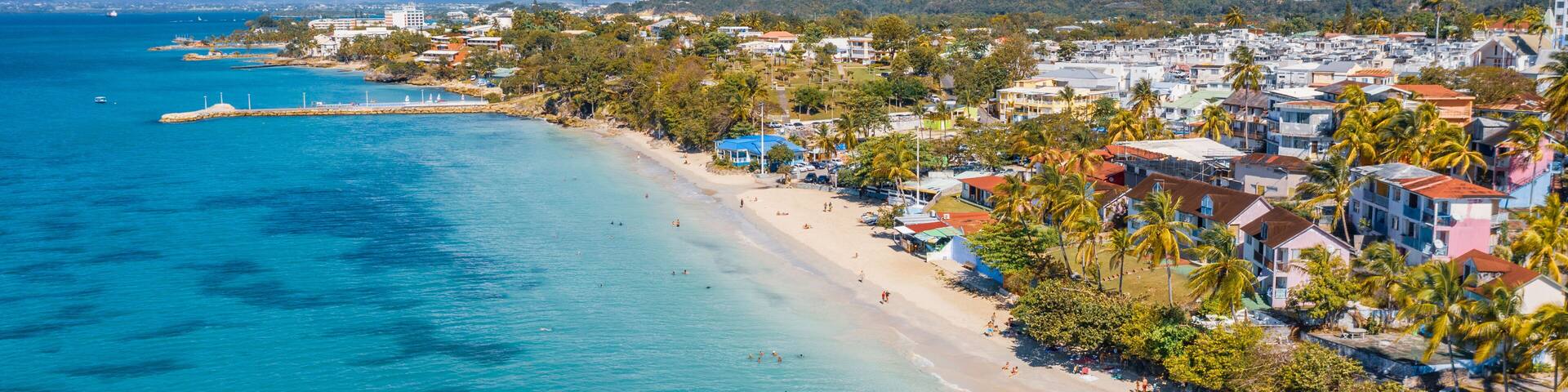 Scenic aerial view of La Datcha beach (Le Gosier plage) in Guadeloupe. Beautiful summer sunny look of small paradise tropical island in Caribbean sea. Several boats and yachts in blue sea.