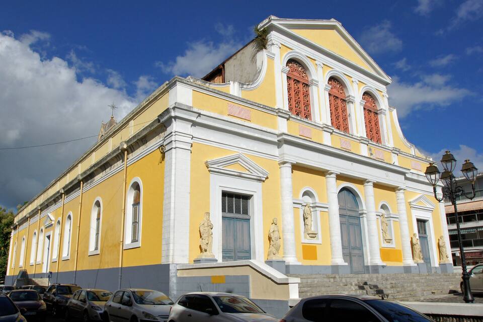 Un bâtiment jaune avec des ornements blancs et des statues sur la façade.