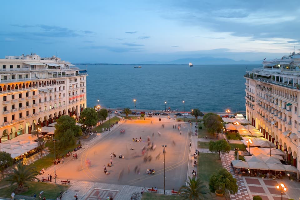 Paisatge urbà costaner amb una gran plaça pública, edificis al front marítim i vista al mar.
