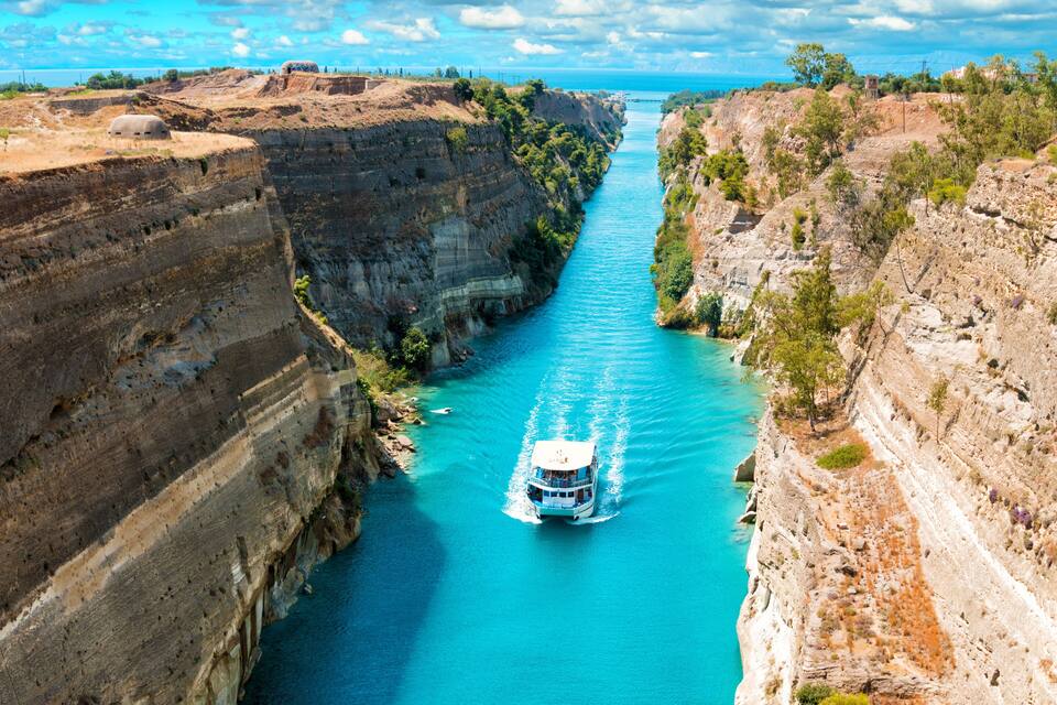 A river canyon with a boat in the middle, surrounded by cliffs and sparse vegetation.