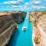 Beautiful scenery of the Corinth Canal in a bright sunny day against a blue sky with white clouds. Among the rocks floating white ship in turquoise water.