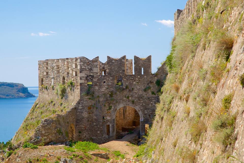 Un château en pierre doté d’une grande entrée en arc de cercle, surplombant une étendue d’eau et une falaise.