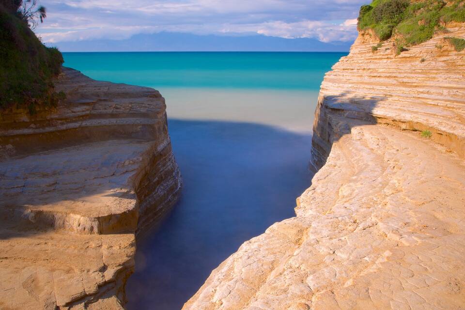 Paisagem costeira com falésias escalonadas e mar calmo.