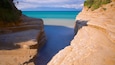 A coastal landscape with layered cliffs and a calm sea.