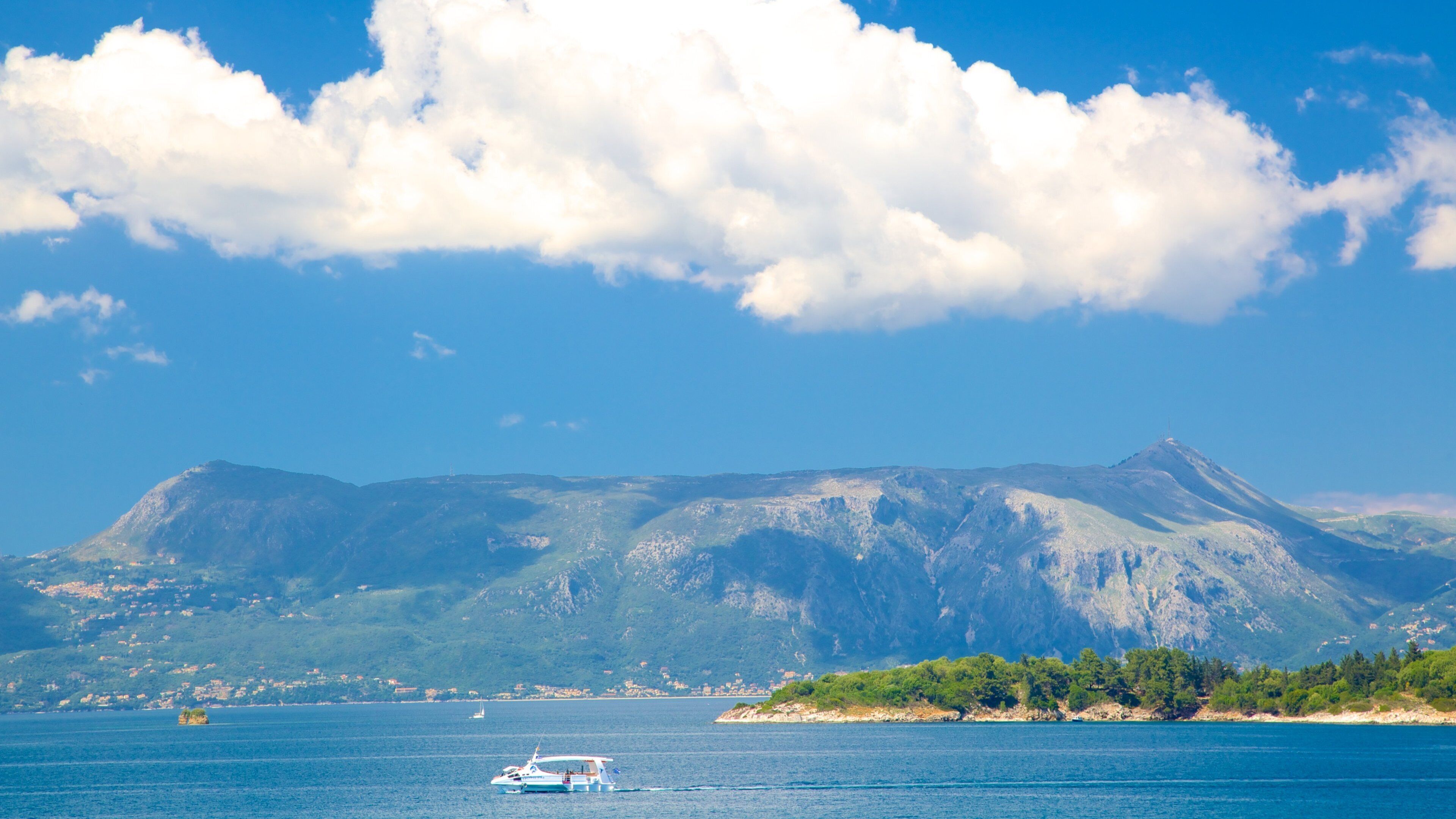 A boat on a calm sea with a mountain range in the background.